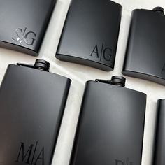 six black flasks sitting on top of a white table next to each other