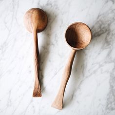 two wooden spoons sitting on top of a white marble counter next to each other