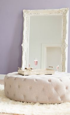 a white ottoman sitting in front of a mirror