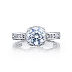 an engagement ring with diamonds on the band and a center stone surrounded by small round stones