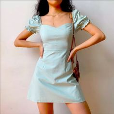 a woman in a short blue dress posing for the camera with her hands on her hips