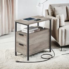 an end table with two drawers and a phone on it in front of a couch