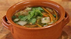 a brown bowl filled with soup on top of a wooden table