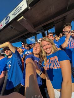 two girls in blue shirts are holding their hands up to the camera and some other people behind them