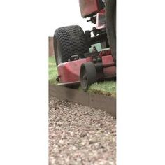 a red lawn mower sitting on top of a grass covered field next to a building