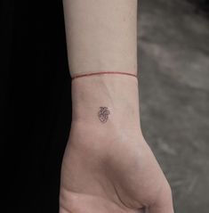 a person's hand with a small heart tattoo on the left side of their wrist