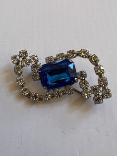 "Elevate your vintage jewelry collection with this stunning Vintage Abstract West Germany Brooch. The blue and clear design exudes a bright and beautiful charm, making it the perfect accessory to add a touch of retro elegance to your sweaters, lapels, scarves, or coats. Stamped West Germany  Approx Measurements 1.75\" Long 1\" Wide Condition: Vintage Excellent.   Sold as is.   PLEASE review all pictures closely.  Contact me with any questions or problems with your order. Thank you for shopping in my store.  International buyers please contact me for shipping details and cost. Most of my items are vintage and used, they will all show some signs of light wear or use.   Major flaws will be noted in the description.  Items are sold \"as is\" so please make sure you look at all pictures careful Blue Costume Jewelry Brooch For Wedding, Blue Brooch For Wedding Jewelry, Vintage Blue Jewelry For Party, Vintage Blue Jewelry For Evening, Blue Vintage Jewelry For Evening, Crystal Costume Jewelry Brooches For Gifts, Blue Wedding Brooch Jewelry, Retro Blue Jewelry For Party, Vintage Blue Brooches For Jewelry Making