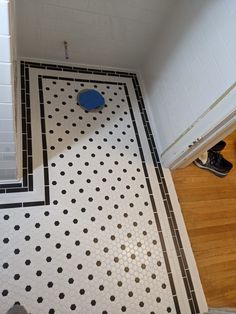 a bathroom with black and white tiles on the floor next to a blue toilet seat