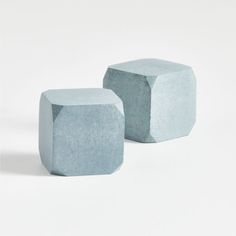 two cement cubes sitting side by side on a white surface, one is grey and the other is light blue