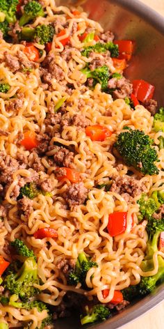 a pan filled with noodles and vegetables on top of a wooden table