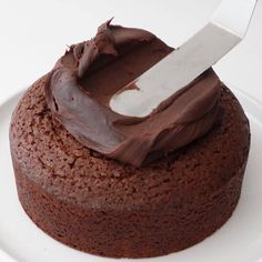 a chocolate cake on a white plate with a knife sticking out of the frosting