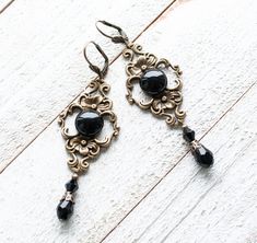 Embrace timeless elegance with our Gothic Chandelier Earrings featuring a round black agate stone set in an antique bronze filigree setting, adorned with black teardrop beads at the bottom. Crafted for those who adore Victorian or vintage style, these elegant earrings measure 2.5 inches in length and an inch wide at the widest part of the filigree setting. Each earring is secured with a comfortable lever back closure, ensuring a snug fit without compromising on style. Experience the allure of vi Black Elegant Chandelier Earrings, Nickel Free, Elegant Black Jewelry With Antique Finish, Black Teardrop Brass Jewelry, Black Metal Jewelry With Antique Finish, Black Gothic Brass Jewelry, Gothic Black Brass Jewelry, Elegant Black Brass Jewelry, Antique Black Drop Earrings, Black Antique Drop Earrings