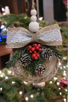 a christmas ornament hanging from a tree with pine cones and berries on it