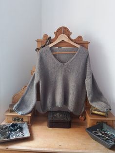 a sweater is sitting on top of a wooden table next to jewelry and other items