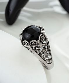 This intricately designed 925 Sterling Silver Filigree Cocktail Ring with a Black Onyx Gemstone is the perfect everyday accessory. The Black Onyx stone is hand cut and polished to a smooth, glossy finish. It is set in a Sterling Silver filigree setting that is oxidized and highly polished. The ring measures 0.55 inches / 13.50 mm in length and width. The Black Onyx Gemstone is 10mm cabochon round-cut. This exquisite ring is sure to add a touch of luxury to your everyday look. Beautifully crafted Art Embroidery, Black Onyx Stone, Unusual Jewelry, Jewelry Techniques, Onyx Gemstone, Sterling Silver Filigree, Ring Black, Filigree Ring, Onyx Stone