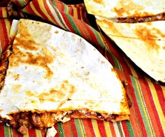 two quesadillas sitting on top of a colorful table cloth