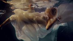 a woman is floating in the water wearing a white dress