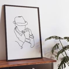 a black and white drawing of a man in a hat on a shelf next to a potted plant