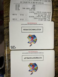 two white business cards with colorful apple logos on them, next to a pair of numbers