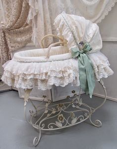 a white crib with a green bow on it's head and some curtains in the background