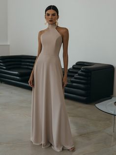 This elegant head-turning dress is tailored from smooth fabric in a figure-skimming silhouette. Defined by an alluring bodice with a halterneck it flows to a stunning flared maxi hem. The dress beautifully showcases an open back and features long ribbon ties at the back of the neck for an elevated finish.- maxi-length hem- slightly close fit- halterneck with long ties at the back- open back- flared hem- concealed zip fastening at the back Cream Gowns Elegant, Beige Long Dress Formal, Beige Long Dresses, High Neck Long Dress, Head Turning Dress, Silk Party Dress, Minimal Dress, Sheer Midi Dress, Halter Top Dresses