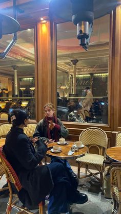 two people sitting at tables in a restaurant