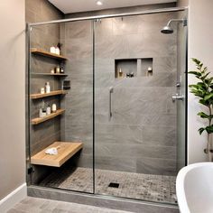 a walk in shower sitting next to a white bath tub under a skylight with candles on the shelves