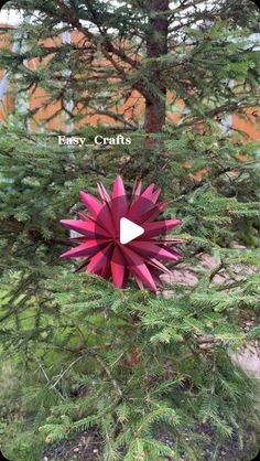 a red origami flower sitting on top of a tree