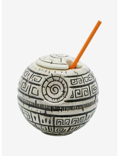 a white and black vase with an orange straw sticking out of it's top