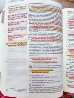 an open bible with red and yellow writing on the pages, next to a cup of coffee