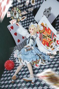 a doll sitting on top of a checkered floor next to playing cards