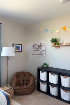 a room with several storage bins on the floor and a chair next to it