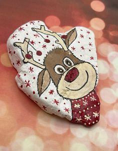 a painted rock with a reindeer on it's face and snowflakes around its neck