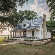 a white house with a metal roof in the middle of a grassy field at sunset