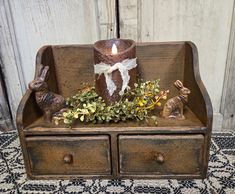 a candle is sitting on top of an old wooden box with some plants and bunnies