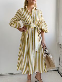 The Ischia Stripe Dress is a shirt dress with flair. Featuring a button down front, shirt collar, tie belt and drop shoulder to an oversized bubble sleeve and pockets. Pair with white tennis shoes or a pair of nude sandals to complete a perfect summer look. Fit: True to sizeFabric Content: 80% Rayon 20% NylonFabric Care: Machine Wash Cold Gentle Cycle, lay flat to dryMeasurements: 45" Shoulder to hemLining: NoZipper: No S:0-2 M:4-6 L:8-10 Yellow Striped Dress, Tee Bag, White Tennis Shoes, Nude Sandals, Sea New York, York Dress, Bubble Sleeve, Mother Denim, Stripe Dress