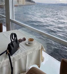 a coffee cup on a table in front of a window overlooking the water and buildings