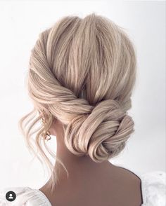 a woman with blonde hair styled into a low updo, wearing a white dress