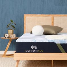 the comfort eco mattress is on display in front of a blue wall and wooden bed frame