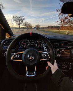 a person driving a car on a road with trees and grass in the back ground