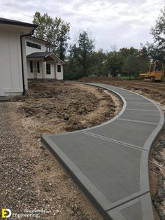 a curved concrete walkway in front of a house with construction equipment on the other side