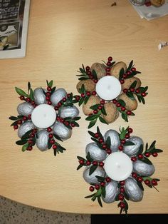 two candles are sitting on top of some rocks with holly and red berries around them