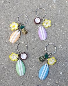 four different colored surfboards and pineapples are on the sand with flower decorations