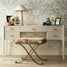 a white table with a bench and some pictures on top of it next to a lamp