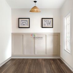 an empty room with two framed pictures on the wall and wood flooring in front of it