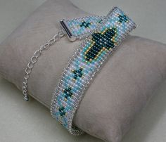 a beaded bracelet is sitting on top of a pillow with a chain attached to it