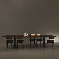 a dining table with four chairs and two candles on it in front of a gray wall