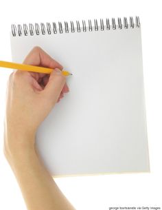 a person holding a pencil and writing on a notepad