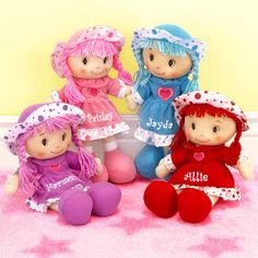 three little dolls are sitting next to each other on a pink rug in front of a yellow wall