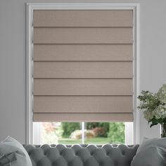 a living room with a couch, window and blinds in shades on the windowsill